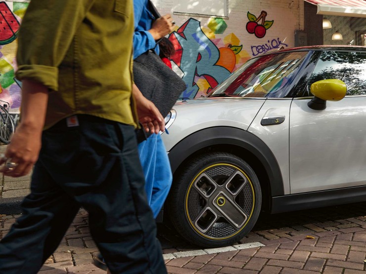 Man en vrouw lopen langs een MINI Electric.